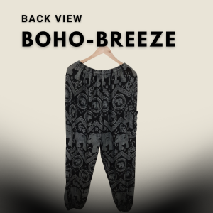 Tall fit black harem pants with elephant and mandala patterns, displayed hanging on a wooden hanger against a light beige gradient background.